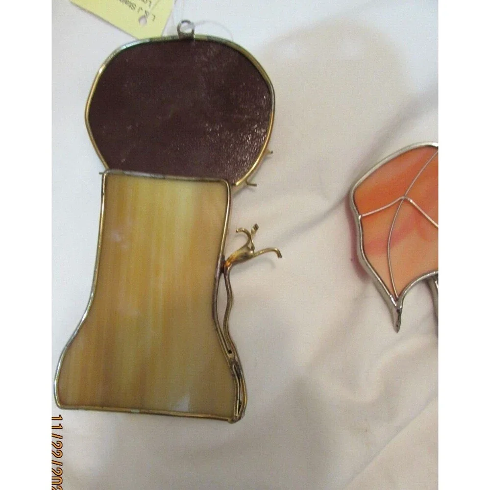 Stained glass leaves and lion handmade ornaments hang in window